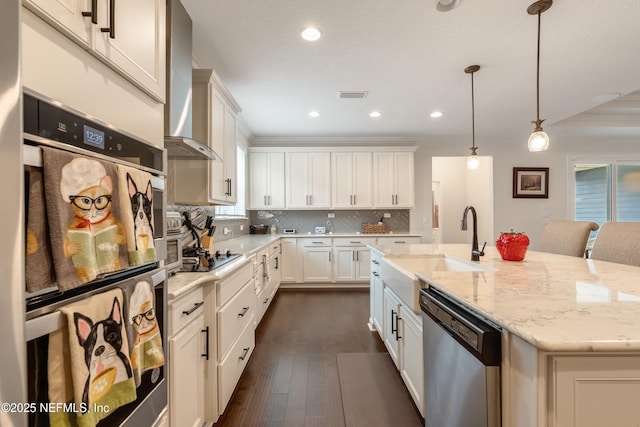 kitchen with decorative backsplash, appliances with stainless steel finishes, an island with sink, and crown molding