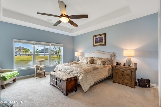 bedroom featuring a tray ceiling, carpet flooring, baseboards, and ceiling fan