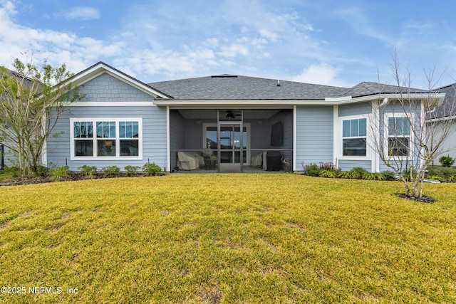 rear view of property featuring a lawn, a shingled roof, and a sunroom