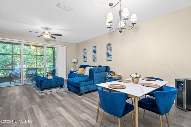 7540 Scarlet Ibis Ln, Jacksonville, FL 32256 - dining space with ceiling fan with notable chandelier, wood finished floors, beverage cooler, and visible vents