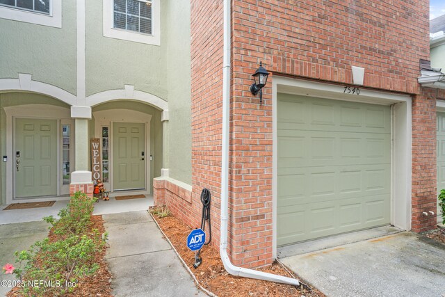 7540 Scarlet Ibis Ln, Jacksonville, FL 32256 - view of exterior entry with stucco siding, a garage, and driveway