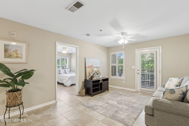 living area featuring light tile patterned floors, baseboards, visible vents, and ceiling fan