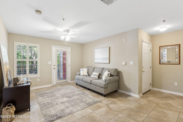 living room featuring light tile patterned flooring, visible vents, baseboards, and a ceiling fan