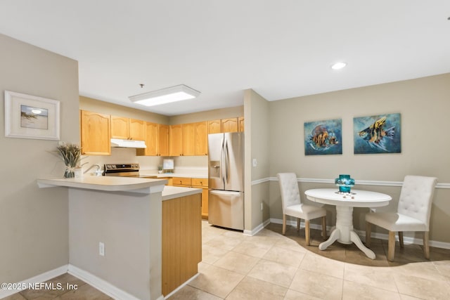 kitchen featuring baseboards, under cabinet range hood, light brown cabinetry, light countertops, and stainless steel appliances