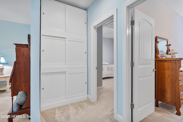 hall with baseboards and light colored carpet