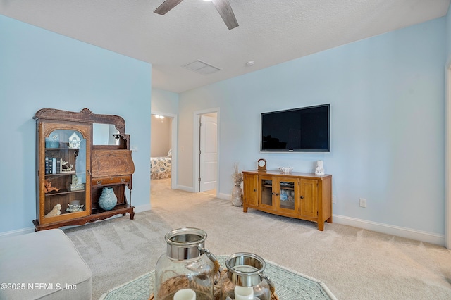 living area featuring visible vents, baseboards, carpet flooring, a textured ceiling, and a ceiling fan