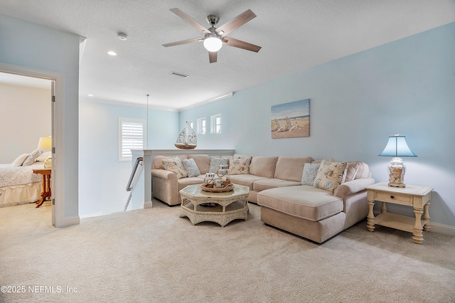 living area featuring carpet, baseboards, visible vents, ceiling fan, and a textured ceiling