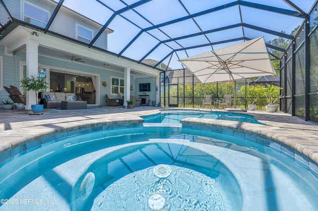 view of pool featuring a pool with connected hot tub, ceiling fan, outdoor lounge area, a lanai, and a patio area