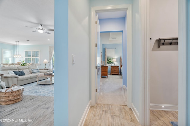 corridor with baseboards and light wood-style flooring