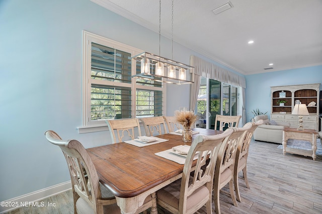 dining space with visible vents, wood finished floors, baseboards, and ornamental molding