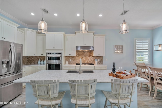 kitchen with under cabinet range hood, crown molding, visible vents, and appliances with stainless steel finishes