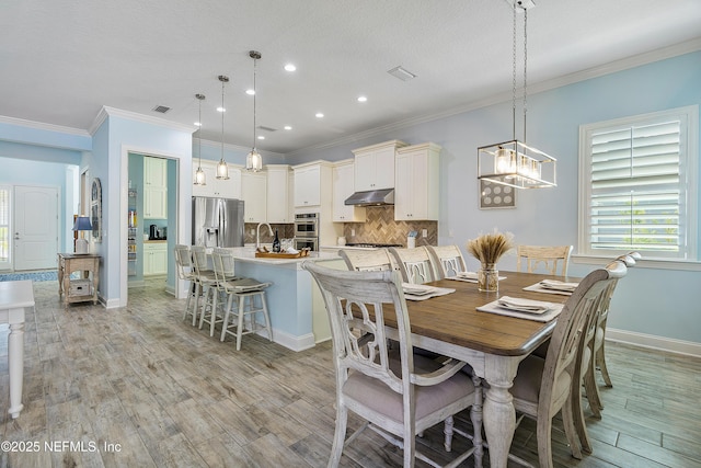 dining area featuring visible vents, baseboards, an inviting chandelier, light wood-style flooring, and ornamental molding