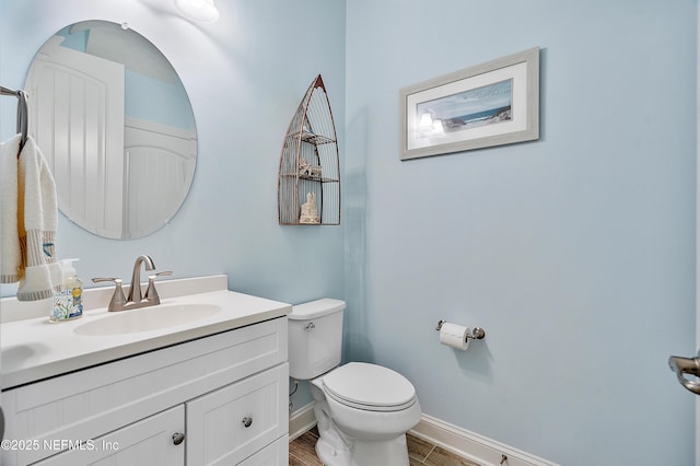 bathroom with baseboards, toilet, wood finished floors, and vanity