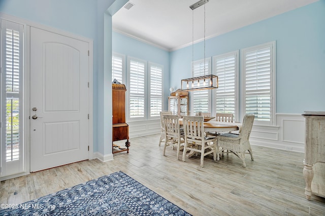 dining room with a notable chandelier, a decorative wall, visible vents, and wood finished floors