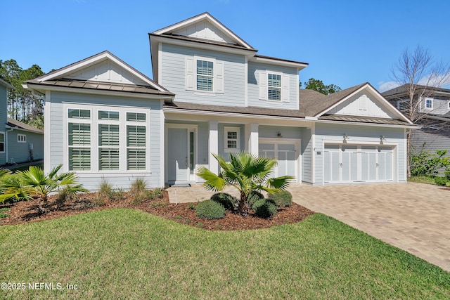 traditional-style home with a standing seam roof, decorative driveway, board and batten siding, a front yard, and metal roof