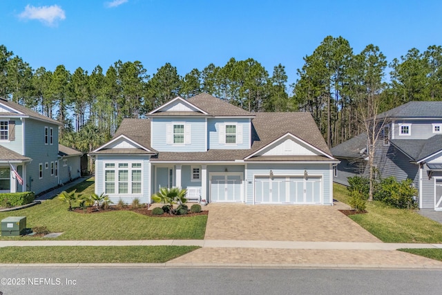 view of front of home featuring driveway, an attached garage, roof with shingles, and a front lawn