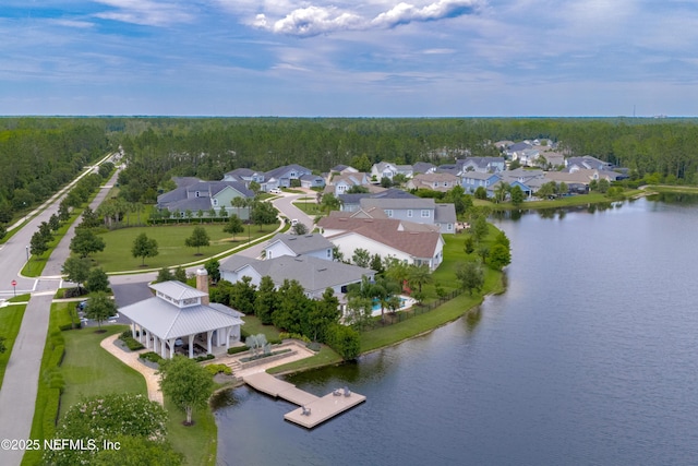 drone / aerial view with a residential view, a wooded view, and a water view