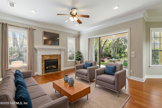 living room with a ceiling fan, visible vents, a wealth of natural light, and light wood-type flooring