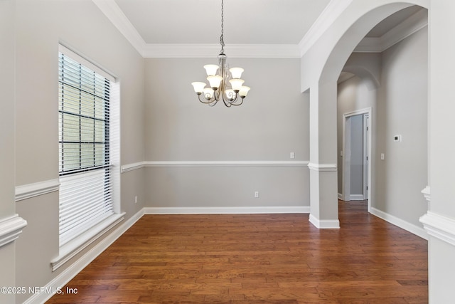 unfurnished dining area featuring a chandelier, ornamental molding, arched walkways, and wood finished floors