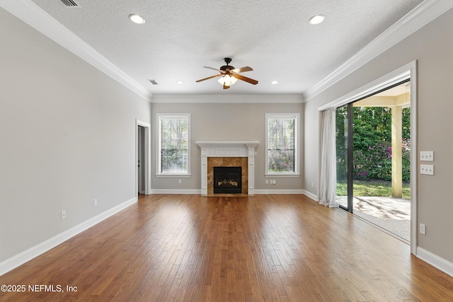 unfurnished living room with plenty of natural light, wood finished floors, a ceiling fan, and a tile fireplace