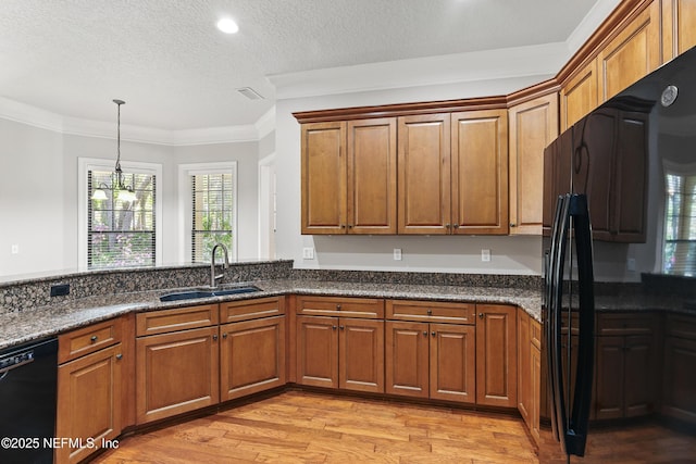 kitchen with light wood finished floors, crown molding, brown cabinetry, black appliances, and a sink