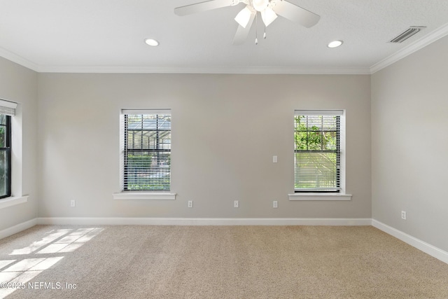 spare room with light colored carpet, crown molding, baseboards, and visible vents