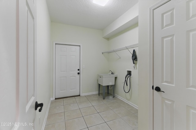 clothes washing area featuring a textured ceiling, light tile patterned floors, baseboards, hookup for a washing machine, and laundry area