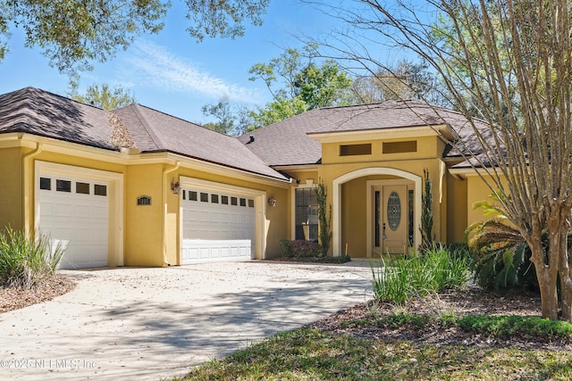 view of front facade featuring a shingled roof, concrete driveway, a garage, and stucco siding