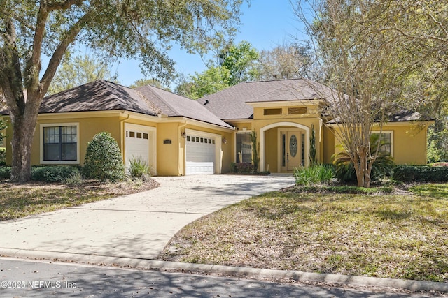 view of front of property with stucco siding, driveway, and a garage