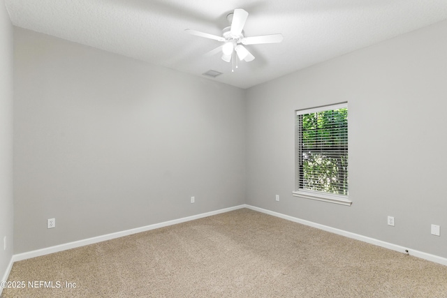 carpeted empty room with visible vents, baseboards, and ceiling fan