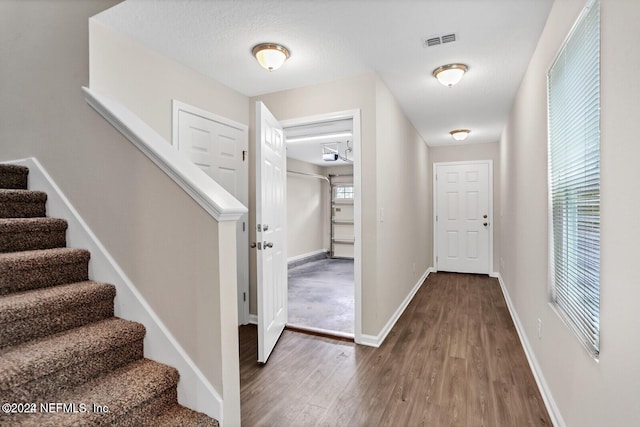 entryway featuring visible vents, baseboards, wood finished floors, and stairway