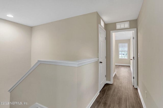 hallway featuring wood finished floors, baseboards, and visible vents