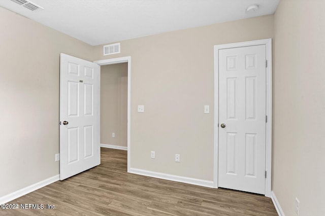 unfurnished bedroom with wood finished floors, visible vents, and baseboards