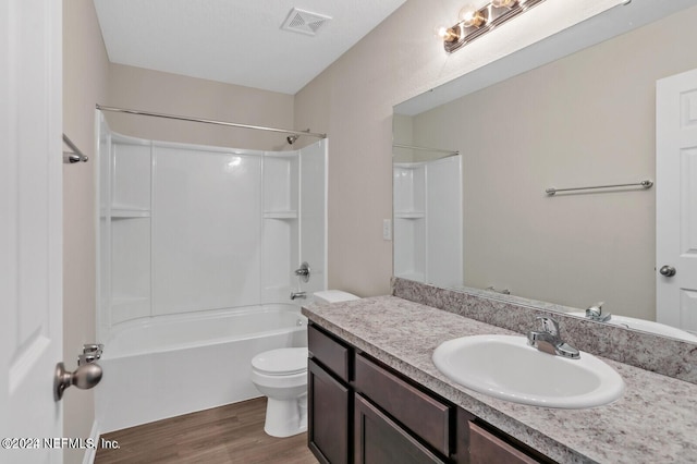 bathroom with vanity, wood finished floors, visible vents,  shower combination, and toilet