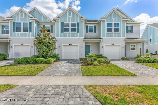 townhome / multi-family property with decorative driveway, board and batten siding, and an attached garage