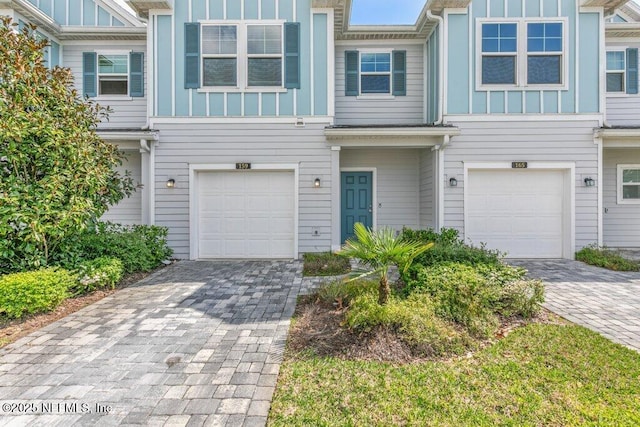 multi unit property featuring decorative driveway, a garage, and board and batten siding