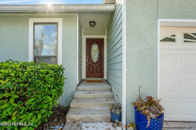 doorway to property with stucco siding and a garage