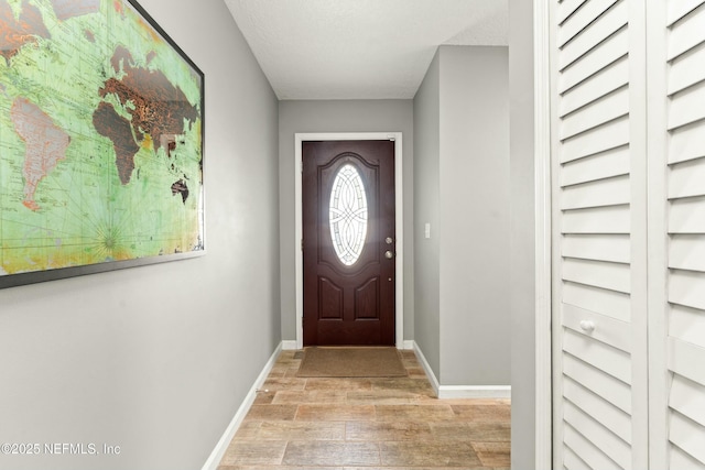 doorway to outside with light wood-style flooring and baseboards