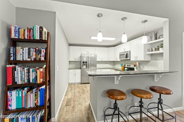 kitchen featuring dark stone counters, light wood-style floors, open shelves, and stainless steel appliances