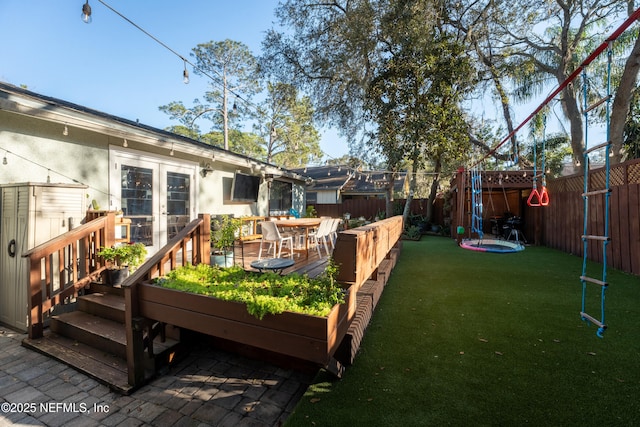 view of yard with a deck, french doors, and a fenced backyard