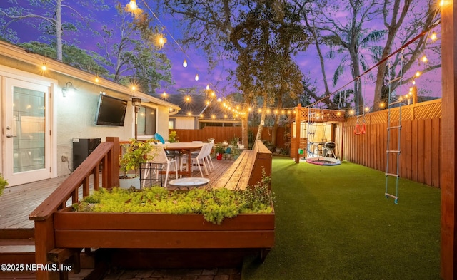 view of yard with outdoor dining area, a fenced backyard, and a wooden deck