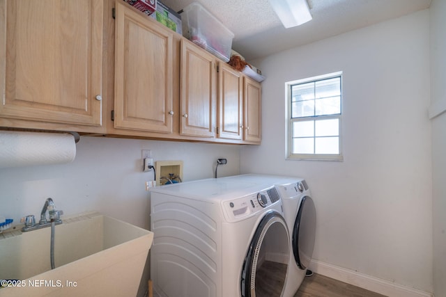 laundry room featuring wood finished floors, baseboards, cabinet space, a sink, and washing machine and dryer