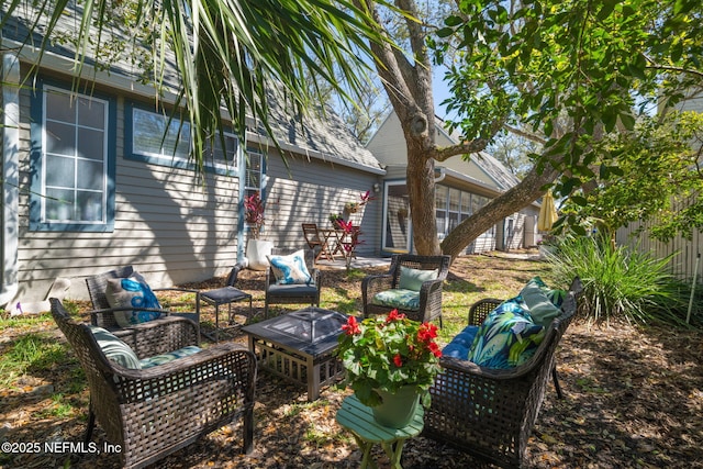 rear view of house featuring an outdoor living space with a fire pit and fence