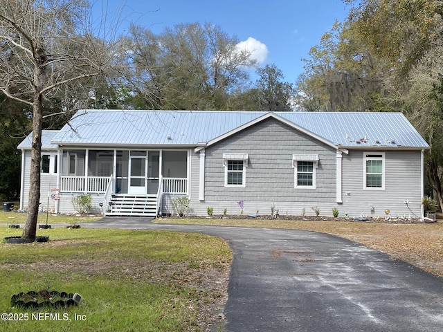 single story home featuring driveway, metal roof, a front yard, and a sunroom