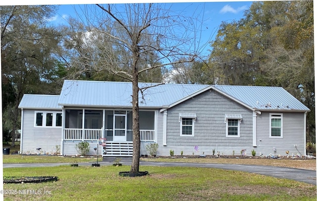 ranch-style home featuring a front yard, driveway, a sunroom, and metal roof