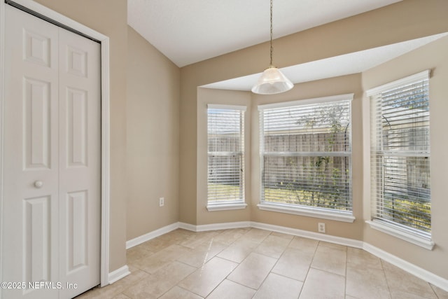 unfurnished dining area with light tile patterned floors and baseboards