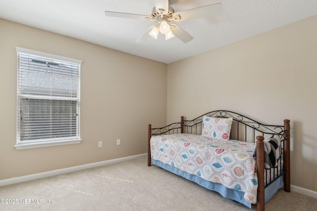 carpeted bedroom featuring a ceiling fan, baseboards, and a textured ceiling