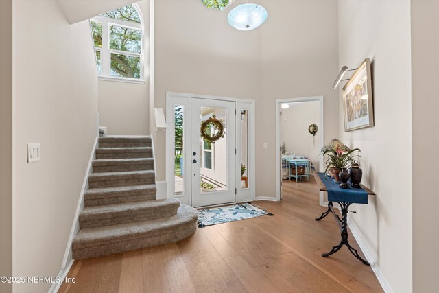 foyer with stairway, baseboards, a towering ceiling, and hardwood / wood-style floors