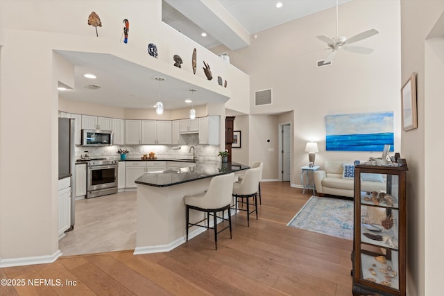 kitchen featuring visible vents, a sink, open floor plan, stainless steel appliances, and a peninsula