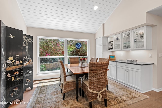 dining room with lofted ceiling, plenty of natural light, baseboards, and light wood-type flooring